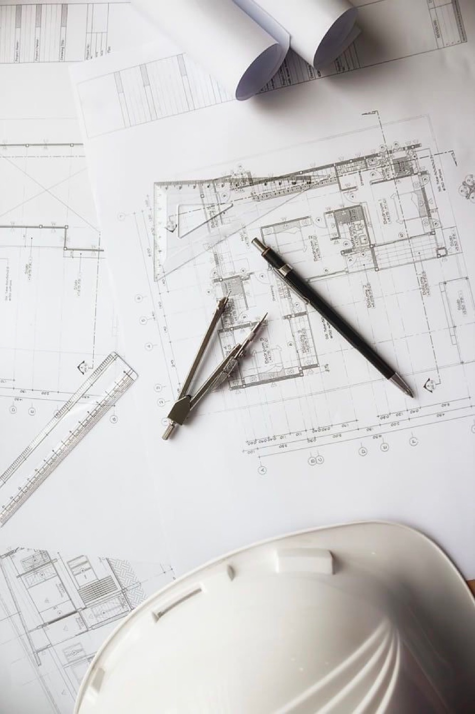 Planos constructivos con instrumentos de dibujo y casco de obra