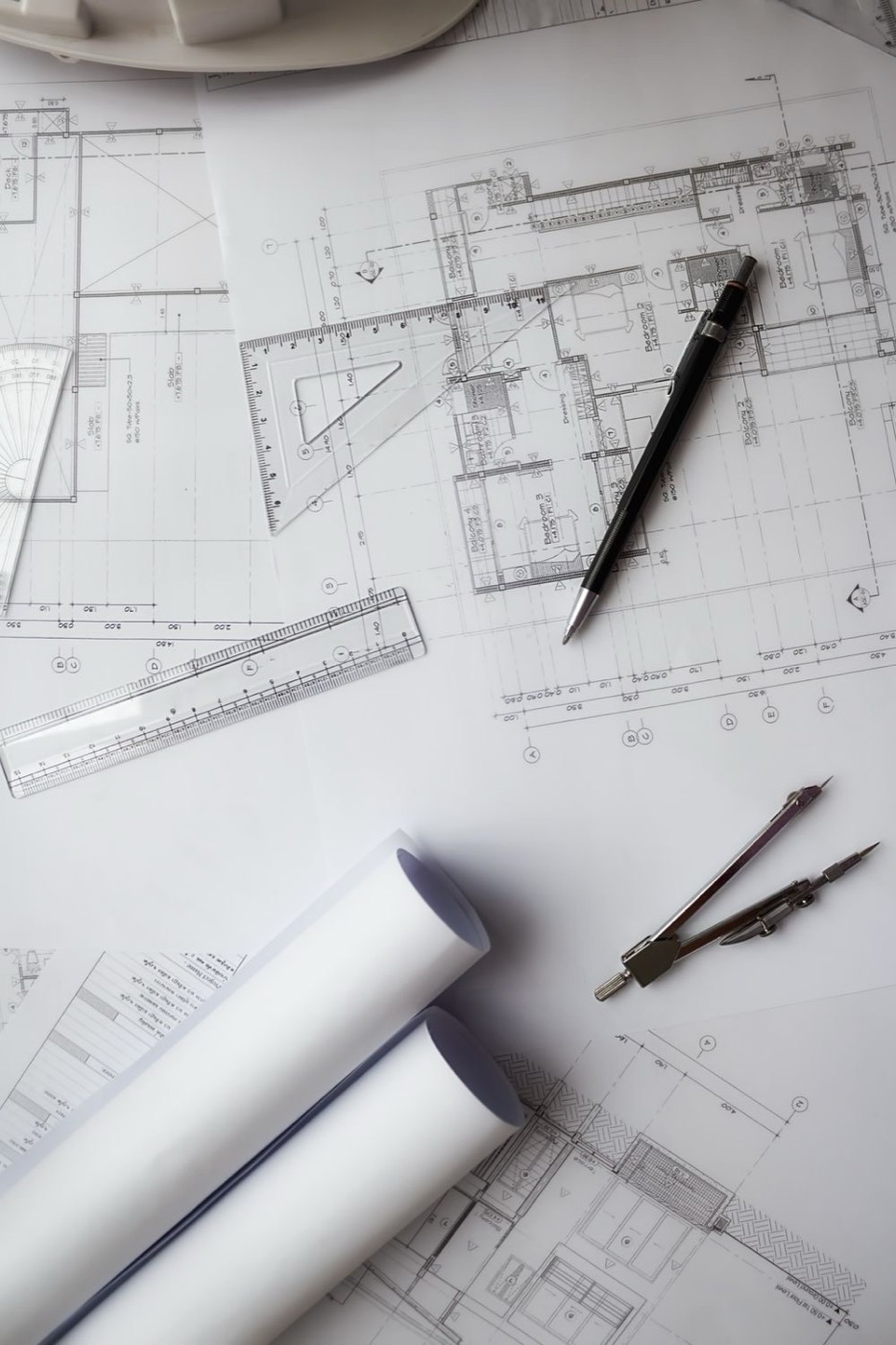 Planos arquitectónicos con reglas, compás y rollos de planos